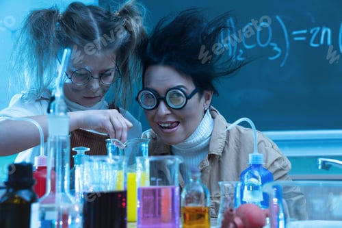 Preview: Teacher and little girl during chemistry lesson mixing chemicals in a laboratory
