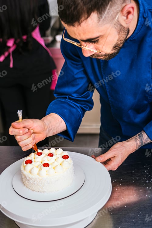 Preview: Pastry chef decorating a coconut cake with fruit syrup