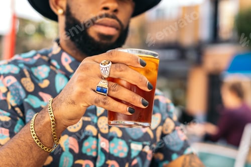 Preview: Black man having a drink in a bar terrace