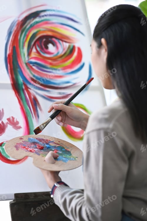 Preview: Rear view of female artist painting with watercolor on canvas.