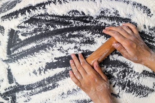 Preview: Female hands keep rolling pin with flour on dark table. Baking background. Flour, cooking and bake