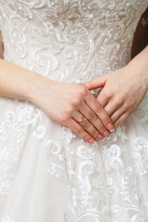 Preview: Bride's hands folded on a white wedding dress