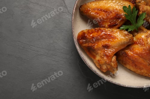 Preview: Bowl with delicious fried chicken wings on black table, top view. Space for text