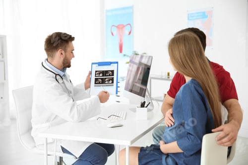 Preview: Gynecology consultation. Doctor showing ultrasound of baby to future parents in clinic