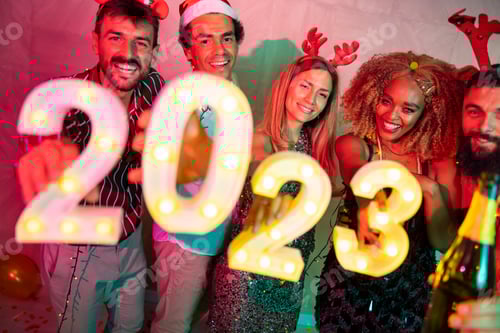Visualização: Amigos segurando números iluminativos de 2023 na festa de Ano Novo