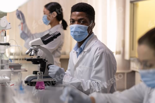 Preview: Young African male chemist in protective workear
