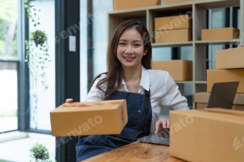 Preview: Portrait business Asian woman with parcel shipping box before send to customer. Entrepreneur small