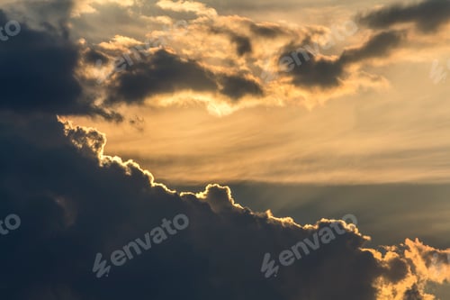 Preview: Beautiful view of dark blue clouds lit by bright orange yellow sun on clear sky.