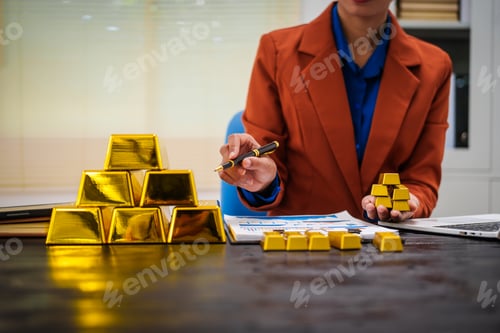 Preview: An Asian businesswoman sitting at her desk in office,analyzing gold bullion prices,market trends