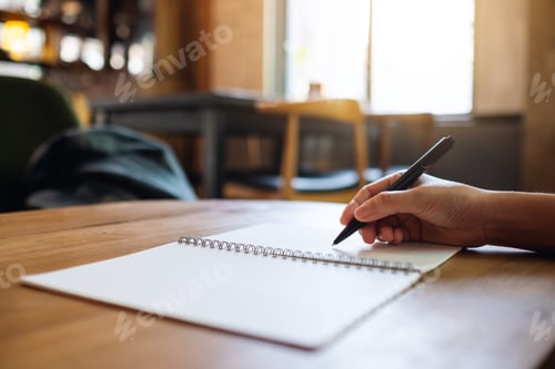 Preview: Closeup image of a woman writing on a blank notebook on the table