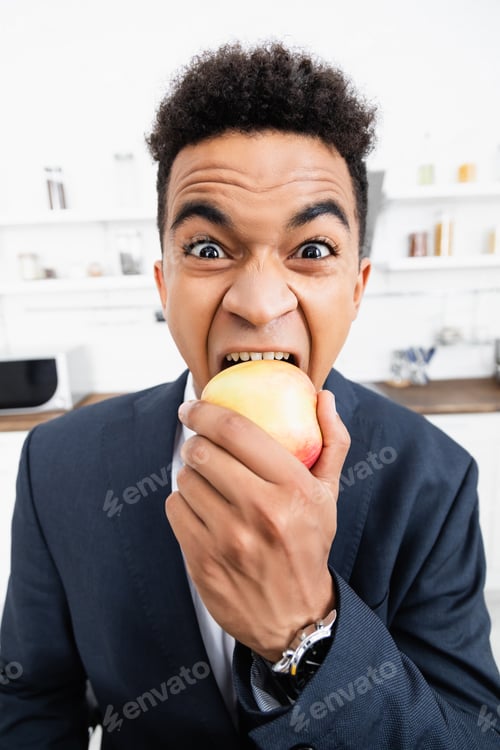 Preview: curly african american businessman eating apple at home