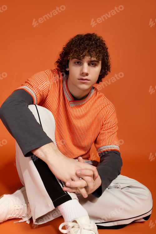 Preview: Casual teenage boy in stylish outfit against bright orange backdrop