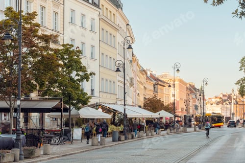 Preview: Golden hour over a bustling city street lined with cafes and historic architecture.
