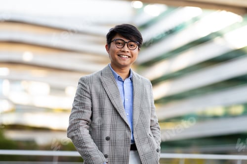 Preview: Professional man smiles confidently outside modern building during daytime
