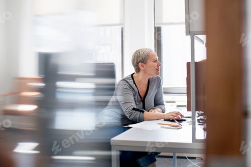 Preview: A woman working in an office at her desk, using a computer mouse.