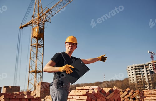Preview: Shows gestures and talks. Construction worker in uniform and safety equipment have job on building