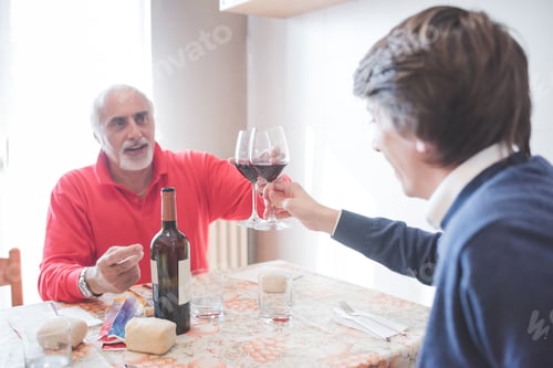Preview: Two man friends or relatives indoors at home having lunch together making toast