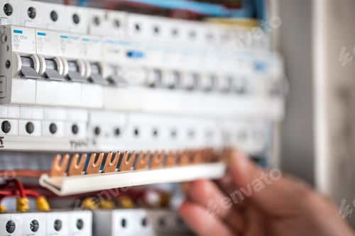 Preview: Man, an electrical technician working in a switchboard with fuses.