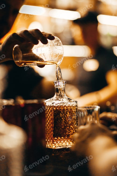 Preview: A bartender pours whiskey from a measuring glass into a decanter