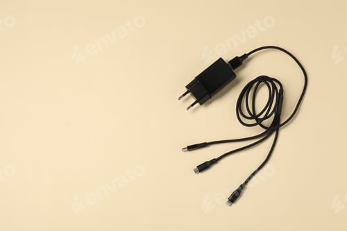 Preview: USB power adapter and triple charge cable on beige background, top view. Space for text