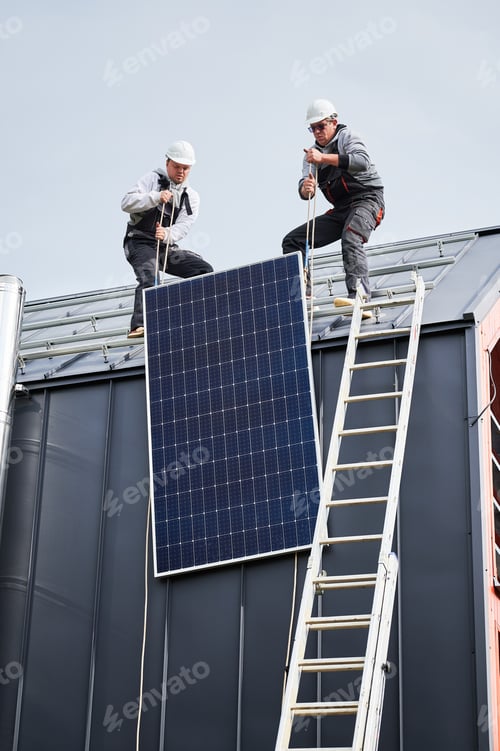 Preview: Workers lifting up photovoltaic solar module while installing solar panel system on roof of house.
