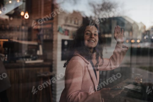 Preview: Young woman drinking tea and looking out of the cafe window while enjoying her leisure time alone