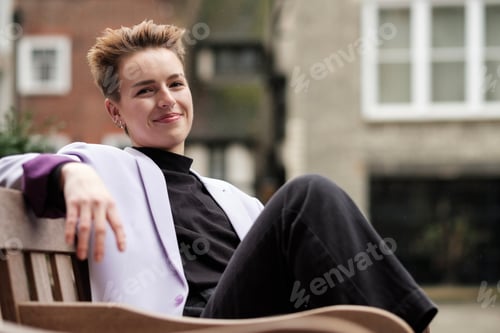 Preview: Relaxed portrait of young woman sitting on bench under the rain.