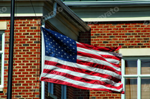 Preview: Waving flag of the United States against a brick wall building