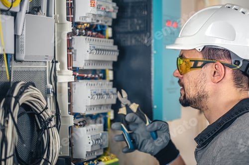 Preview: Man, an electrical technician working in a switchboard with fuses.