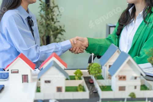 Preview: Two businesswomen sit at a table in the office,discussing a model village with windmills