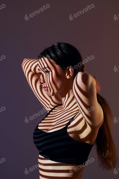 Preview: Lines is on the skin. Beautiful young woman is in projector neon lights in the studio