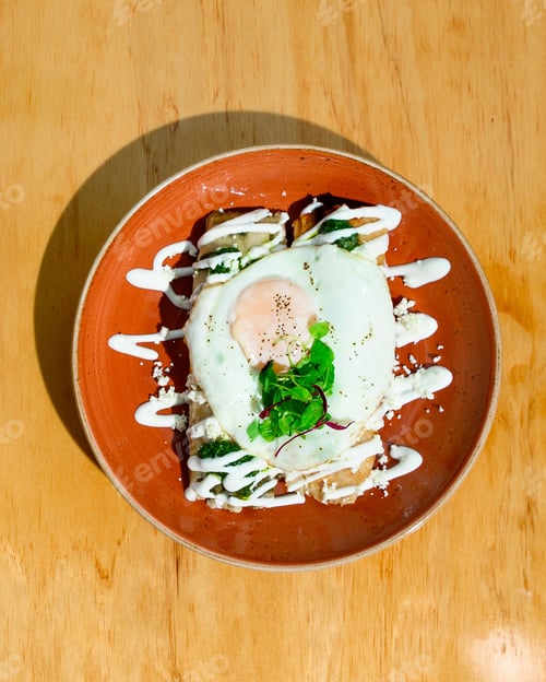 Preview: Top view of a fried egg with veggies and sauces on a plate on the table