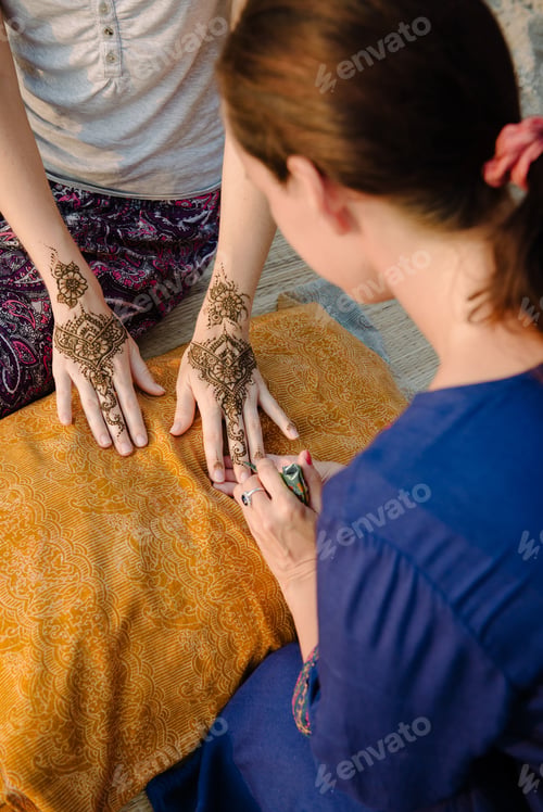 Preview: Artist applying henna tattoo on women hands. Mehndi is traditional Indian decorative art. From artis