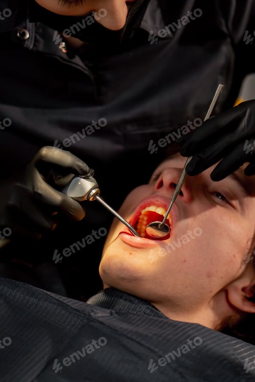 Preview: dental office girl doctor examines the oral cavity using a mirror and a machine with air