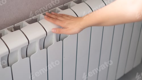 Preview: woman's hand touches the radiator. hot radiator, heating season concept
