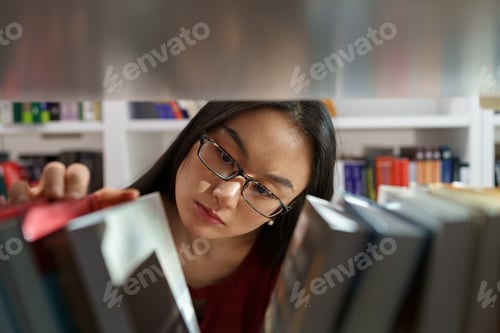 Preview: Asian girl choosing book while in bookstore, female student searching for primary sources in library