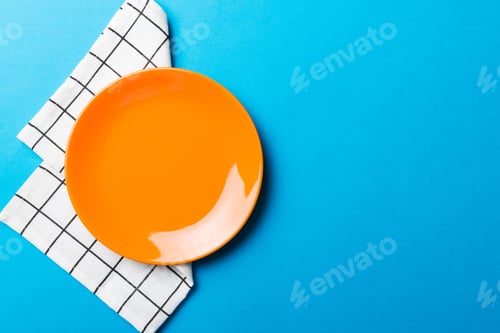 Preview: Top view on colored background empty round red plate on tablecloth for food.
