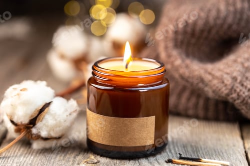 Preview: Fall or winter season cozy evening with candles. Soy wax candle in a dark glass jar with label