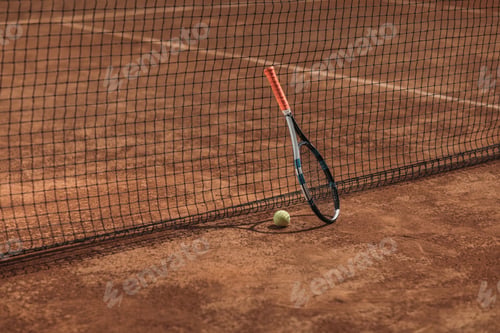 Preview: tennis ball and racket leaning on net