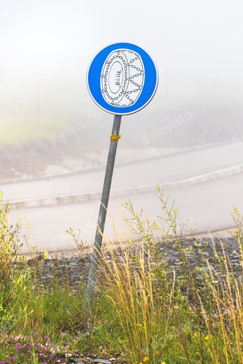 Preview: European mandatory snow chain wheels traffic sign in winter on cold foggy morning