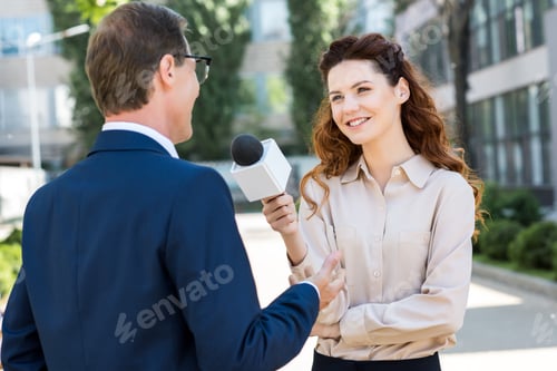 Preview: smiling female journalist taking interview with businessman