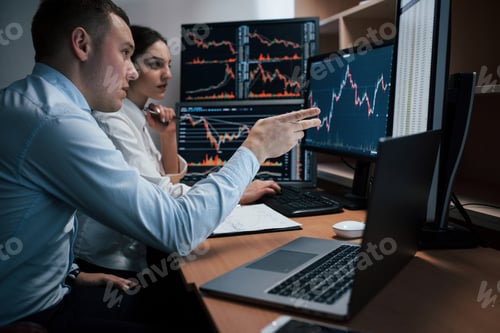 Preview: Team of stockbrokers are having a conversation in a office with multiple display screens
