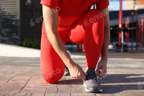 Preview: Woman tying shoelaces before running outdoors, closeup