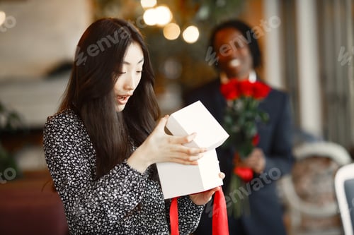 Preview: Happy Chinese girl received a gift from an African in a cafe