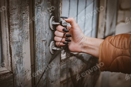 Preview: Halloween horror concept background. witch hand with black nails opens old wooden door spider web.