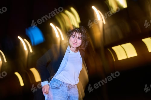 Preview: Young woman posing at night with city lights blurred in background