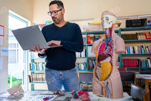 Preview: Teacher preparing lessons with a laptop and anatomical models in a classroom
