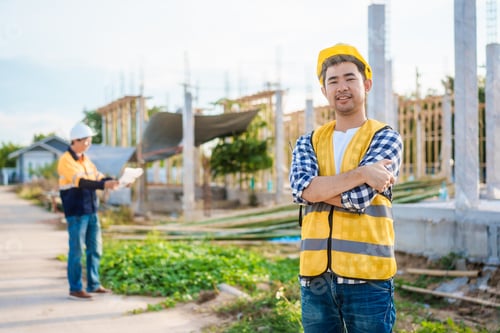 Preview: An Asian middle-aged male engineer wearing safety helmet and reflective vest uses walkie-talkie