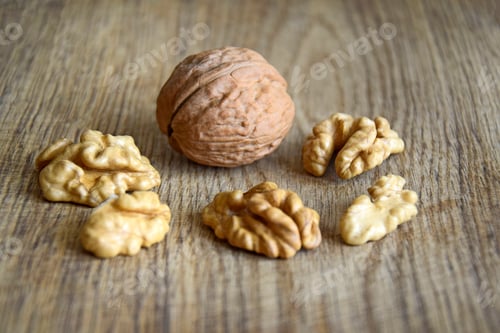 Preview: One whole walnut with kernels on wooden background, organic food, selective focus. Copy space.