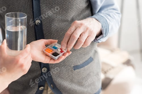 Preview: Cropped view of nurse giving pills to senior man
